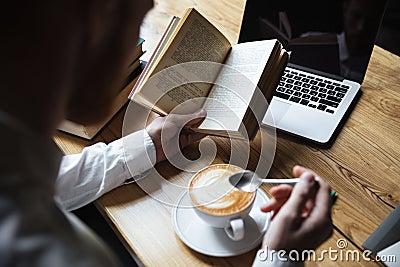 Top view of man in white shirt stirring coffee while reading boo Stock Photo