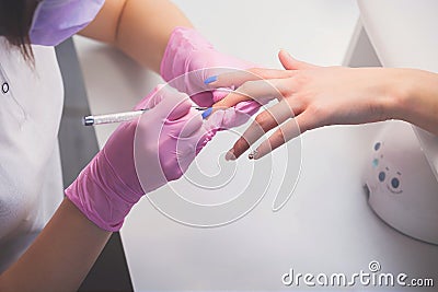 Top view of manicurist in pink rubber gloves and medical mask makes hand painting fingernails with brush Stock Photo