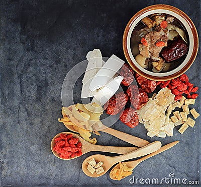 Top view of many chinese herbs with bowl of clear soup on black Stock Photo