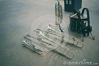 Top view of marching band instruments: trombones, trumpets, saxophones and euphonium drums laying on the floor. Stock Photo