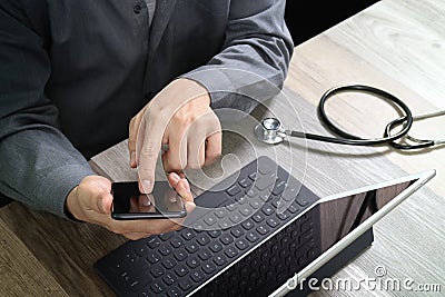 top view of medical doctor hand working with smart phone,digital tablet computer,stethoscope eyeglass,on wooden desk Stock Photo