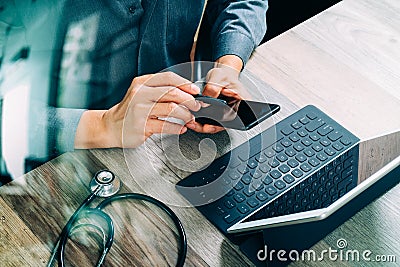 top view of medical doctor hand working with smart phone,digital tablet computer,stethoscope eyeglass,on wooden desk,filter Stock Photo