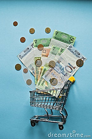 Top view mini shopping cart with Coins on blue table. Stock Photo