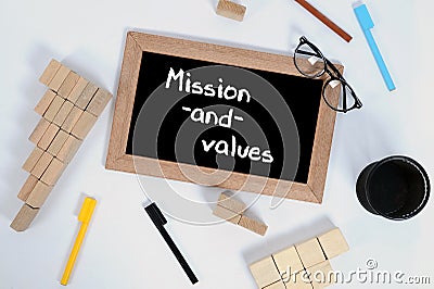 Top view of MISSION AND VALUES written on a blackboard. Pencil cup, glasses, color marker and Wood block stacking as step stair Stock Photo