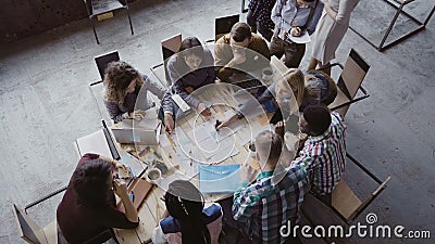 Top view of mixed race business team sitting at the table at loft office and working. Woman manager brings the document. Stock Photo