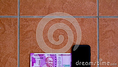 Top view of the new Rs 2000 currency bill kept alongside a smartphone. The new bill was introduced in India after demonetization Stock Photo