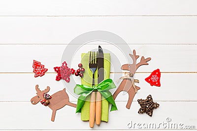 Top view of new year utensils on napkin with holiday decorations and reindeer on wooden background. Christmas dinner concept with Stock Photo