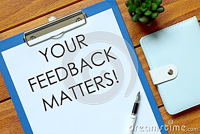 Top view of notebook,plant,pen and clipboard written with Your Feedback Matters on wooden background. Stock Photo