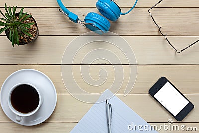 Top view notepaper,headphones,smartphone,pen,coffee ,cactus,eyeglasses on office desk background. Stock Photo