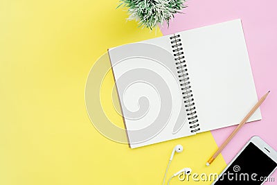 Top view office desk with notebooks, plant, mock up phone, earphone and copy space on pastel color background. Stock Photo