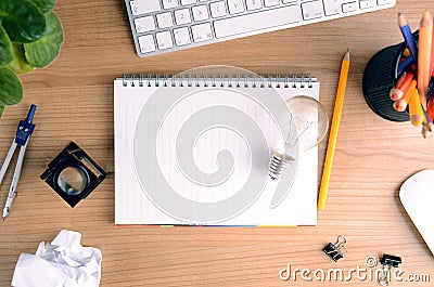 Top view of office desk with paper, stationery, computer, flower, blank notepad and light bulb Editorial Stock Photo