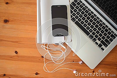 Top view of an office mock up with a laptop, blank mobile phone with headsets, and blank notebook Editorial Stock Photo