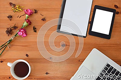 Top view of an office table mock up with a laptop, blank notebook, tablet, a cup of coffee and flowers with copy space at the cen Editorial Stock Photo