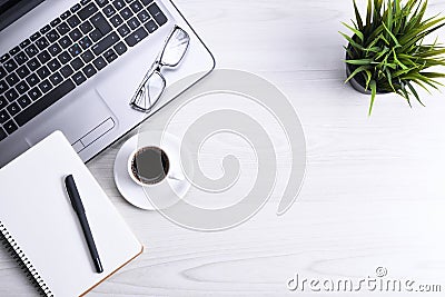 Top view of office work space, wooden desk table with laptop notebook,keyboard ,pen,eyeglasses,phone,notebook and cup of coffee. Stock Photo