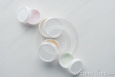 top view of open bottles of cream on white surface Stock Photo