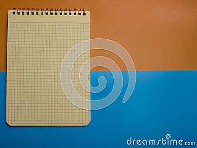 Top view of an open notebook with a pencil and an eraser on a blue-yellow background. Stock Photo