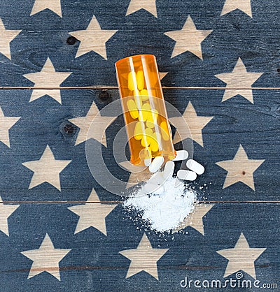 Top view of open prescription bottle filled with opioid pain killer tablets with USA rustic flag in background Stock Photo