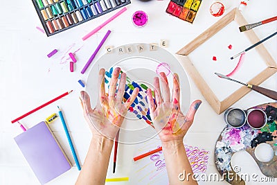 Top view opened painted female hands over Create word lettering with many colorful paintiing materials on white background. Create Stock Photo
