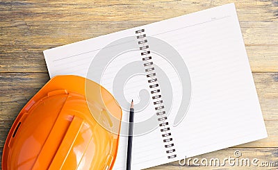 Top view with orange safety engineer helmet and notebook on wood Stock Photo