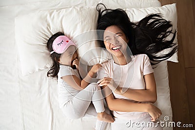 Happy Asian mom and little daughter relax in cozy bedroom Stock Photo