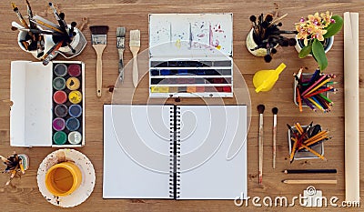 Top view of a painter workplace. Wooden desk with watercolor, aquarelle and gouache colorful paints palette for hobby. Stock Photo