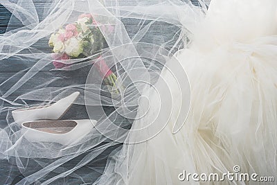 top view of pair of shoes, wedding dress and bouquet on wooden dark Stock Photo