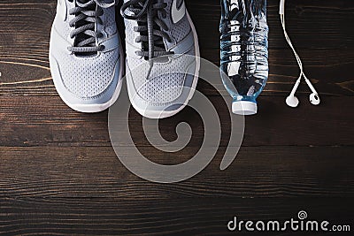 Top view of pair sports shoes, headphones and water bottle on black wood table background, Gray sneakers and accessories equipment Stock Photo