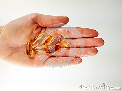 Top view of a palm hand on white background holding handful of omega pills capsules as healthy cure, supplement and prevention Stock Photo