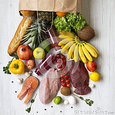 Top view, paper bag of healthy raw food on a white wooden table. Cooking food background. Fresh fruits, veggies, greens, different Stock Photo