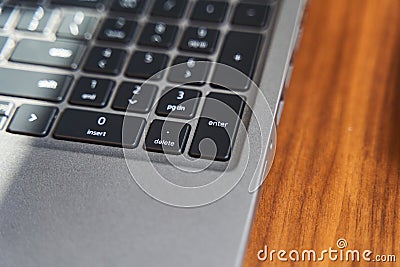 Top view of a part of a gray laptop keyboard on a wooden table Stock Photo
