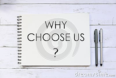 Top view of pen and notebook written with question Why choose us? on white wooden background. Stock Photo