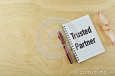 Top view of pen and notebook written with TRUSTED PARTNER Stock Photo