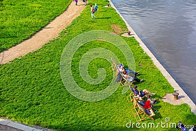 Top view, people are resting on wooden chairs on the lawn by the river Editorial Stock Photo