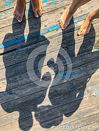 Top view, photo of bare feet and a pair of shadows on a wooden old floor. Photos on vacation, beach, summer Stock Photo