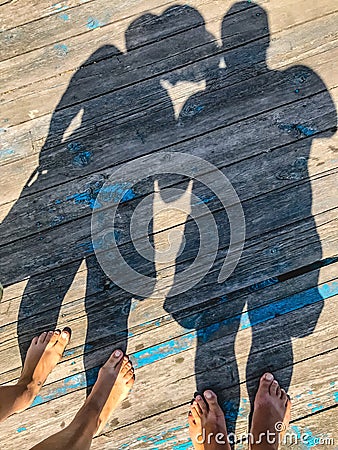 Top view, photo of bare feet and a pair of shadows on a wooden old floor. Photos on vacation, beach, summer Stock Photo