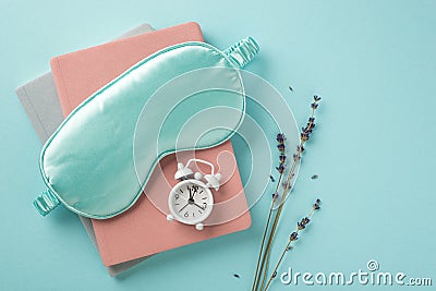 Top view photo of blue silk sleeping mask small white alarm clock on planners and sprig of lavender on isolated pastel blue Stock Photo