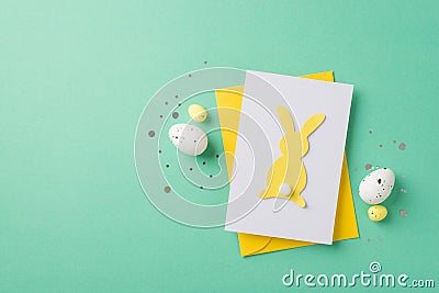 Top view photo of easter decorations shiny confetti yellow envelope paper card with easter bunny silhouette and easter eggs on Stock Photo