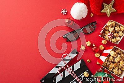 Top-view photo showcasing a movie clapper, 3D glasses, popcorn, Santa's hat, baubles, star decor on a red background Stock Photo