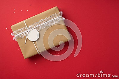 Top view photo of valentine`s day decorations sequins craft paper giftbox with lace ribbon trim and pricetag on isolated red Stock Photo