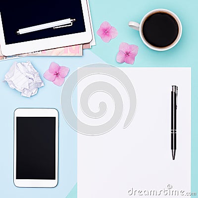 Top view photo of workspace with blank mock up tablet and smartphone, coffee cup, notepad and woman fashion magazines. Stock Photo