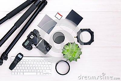 Top view of photographer workplace with dslr camera, lens and camera accessories on white wooden table. Stock Photo