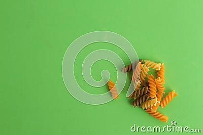 Top view of a pile of colorful raw rotini pasta on a green background Stock Photo