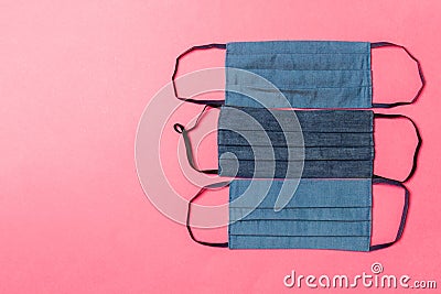 Top view of a pile of homemade textile reusable masks on pink background. Respiratory protection concept with copy space. DIY Stock Photo