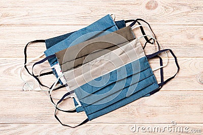 Top view of a pile of homemade textile reusable masks on wooden background. Respiratory protection concept with copy space. DIY Stock Photo