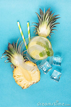 Top view of pineapple half with healthy smoothie and ice cubes o Stock Photo