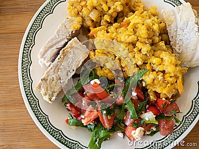 Plate with red lentil, tomato salad and slices of steamed pork Stock Photo