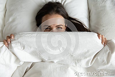 Top view playful cute young woman peeking from blanket Stock Photo