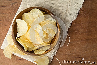 Top view of potato chips in wooden bowl putting on linen and wooden background Stock Photo
