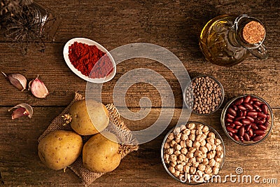 Top view of potatoes, 3 bowls of chickpea, red beans and lentil and other ingredients on the table Stock Photo