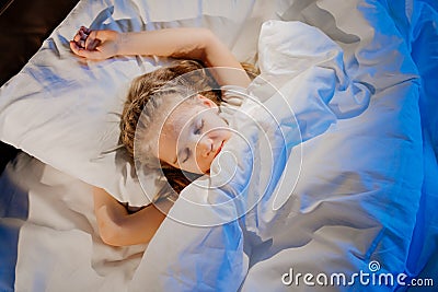 Top view. pretty girl naps in bed, sees pleasant sleep and smiles. Stock Photo